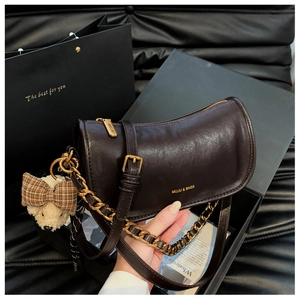 Close-up of retro brown oil wax leather baguette bag with chain and teddy bear charm