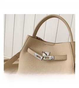 Close-up of the silver hardware twist lock on a beige lychee pattern leather bucket bag
