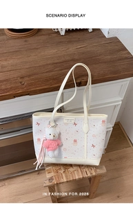 Dettaglio borsa tote beige con stampa cupcake, fiocco rosa e decorazione con ciondolo orso