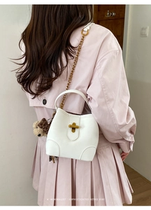 Détail du sac seau en cuir blanc avec breloque léopard et bandoulière chaîne