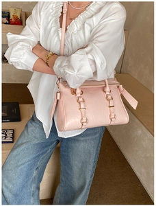 Dettaglio della borsa rosa in pelle martellata con anelli dorati e tracolla lunga
