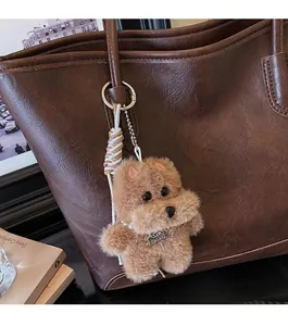 Detalle de un colgante de peluche para bolso con collar de perlas en un bolso de cuero