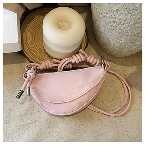 Sacoche rose en cuir avec bandoulière nouée et détails argentés sur lin beige clair