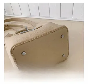 Detail view of beige leather bucket bag base featuring four silver metal protective feet