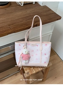 Dettaglio della borsa tote stampata con motivi a fiocco rosa e ciondolo a forma di orso