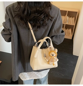 Détail du sac à main en cuir grainé blanc cassé avec pendentif ours en peluche et fermoir
