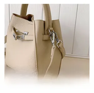 Detail of beige lychee leather handbag showing silver twist lock and premium metal hardware