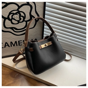 Vue détaillée du sac seau noir en cuir avec bandoulière marron et fermoir en métal doré