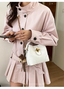 Sac seau blanc avec serrure en métal doré et pendentif ours léopard porté à l'épaule