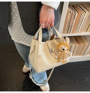 Détail d'un sac seau beige en cuir avec fermoir argenté et breloque ourson mignonne