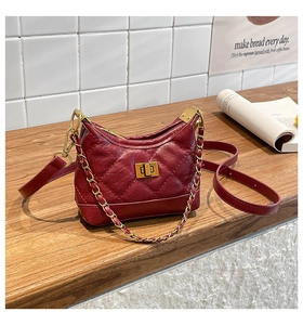 Close-up of dark red quilted bag with gold chain strap and metal twist lock detail