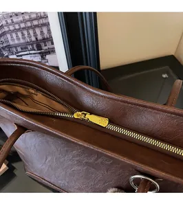 Primer plano de la cremallera dorada suave en un bolso tote de cuero marrón