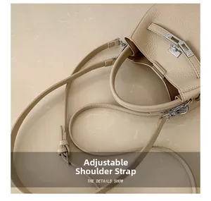 Detailed view of silver metal buckle and adjustable shoulder strap on lychee leather bag