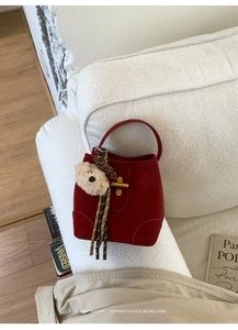 Détail d'un sac seau rouge en daim avec fermoir doré et pendentif en forme d'ours