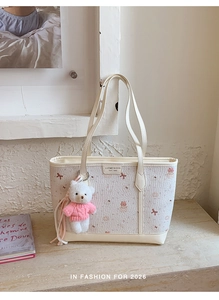 Dettaglio borsa shopper color crema con fiocchi rosa e ciondolo orsetto di peluche