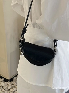 Petit sac demi-lune minimaliste en cuir noir avec bandoulière à nœud sur modèle