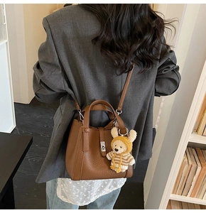 Sac seau en cuir grainé marron avec charm ours porté sur le dos par le mannequin