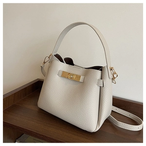 Détail du sac seau en cuir grainé beige avec fermoir rotatif doré et poignée élégante