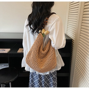 Detail view of khaki crochet hobo bag with dark brown wooden bead strap on model
