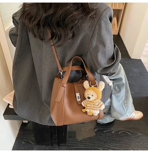 Sac seau marron en cuir grainé avec pendentif ourson porté par un mannequin