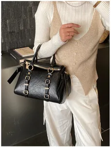 Dettaglio della texture in pelle nera pieghettata e fibbia dorata sulla borsa tote