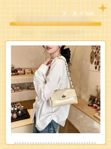 Detail view of cream leather shoulder bag with metal clasp and chain strap for women