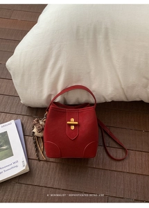 Détail du sac seau rouge foncé avec fermoir doré et accessoire de sac nœud en peluche