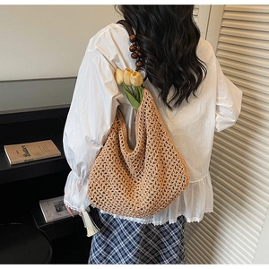 Brown woven shoulder bag with beaded strap shown on a model in a minimalist setting