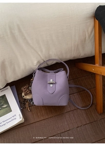 Détail du sac seau lavande avec breloque léopard et fermoir doré sur fond de bois naturel