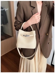 Detail of cream leather bucket bag with silver twist lock and shoulder strap on model