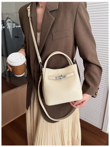 Detail of cream lychee leather bucket bag with metal lock shown in a lifestyle setting