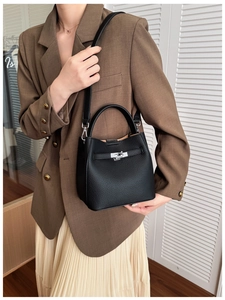 Detail of black lychee grain leather bucket bag with silver rotating metal lock and strap
