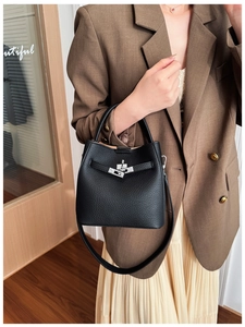 Detail of black pebbled leather bucket bag with silver turn-lock and adjustable strap