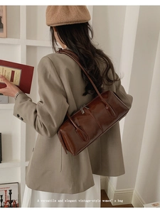 Detailed view of dark brown vintage leather shoulder bag styled with a beige blazer