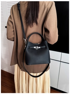 Detail of black lychee leather bucket bag with silver rotating lock and adjustable strap