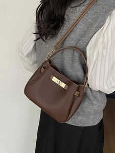 Sac seau en cuir marron avec fermoir doré porté par un mannequin femme