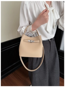 Close-up of beige lychee grain leather bucket bag with silver metal swivel lock detail