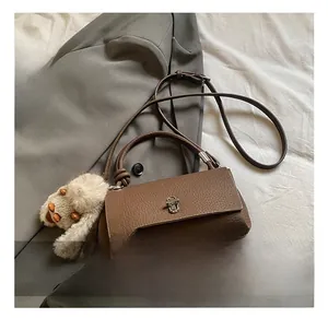 Detail view of dark brown lychee pattern leather bag with silver twist lock and bunny charm