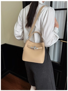 Close-up of beige lychee grain leather bucket bag with silver metal swivel lock hardware