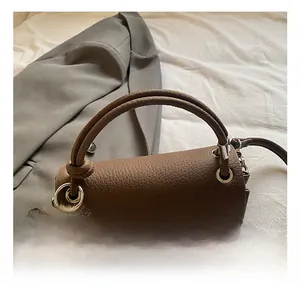 Close-up of brown litchi pattern leather handbag with a plush bunny charm and silver hardware