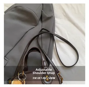 Detail of adjustable shoulder strap and bronze metal hardware on dark brown leather bag
