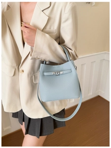 Close-up of light blue litchi grain bucket bag featuring a metal twist lock and leather strap