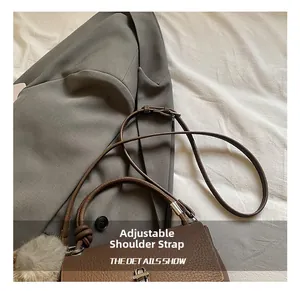 Detail showing the adjustable leather strap and metal buckle of the brown crossbody bag