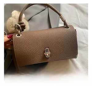 Close-up of the silver metal twist lock and lychee grain leather on a brown handbag