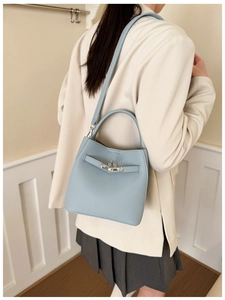 Detail shot of light blue lychee pattern leather bucket bag with silver buckle and strap