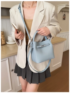 Close-up of light blue pebbled leather bucket bag with silver twist lock and slim strap