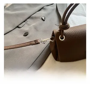 Close-up of silver metal hook and premium lychee grain leather on dark brown handbag