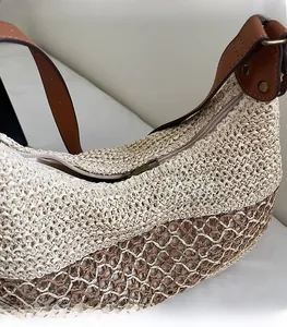 Detailed close-up of smooth metal zipper and woven texture on a straw shoulder bag