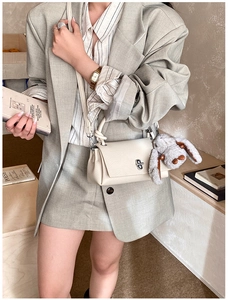Detail of cream leather crossbody bag with silver twist lock and grey bunny charm