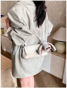Chic beige crossbody bag with pebbled leather texture, silver clasp and plush bunny charm